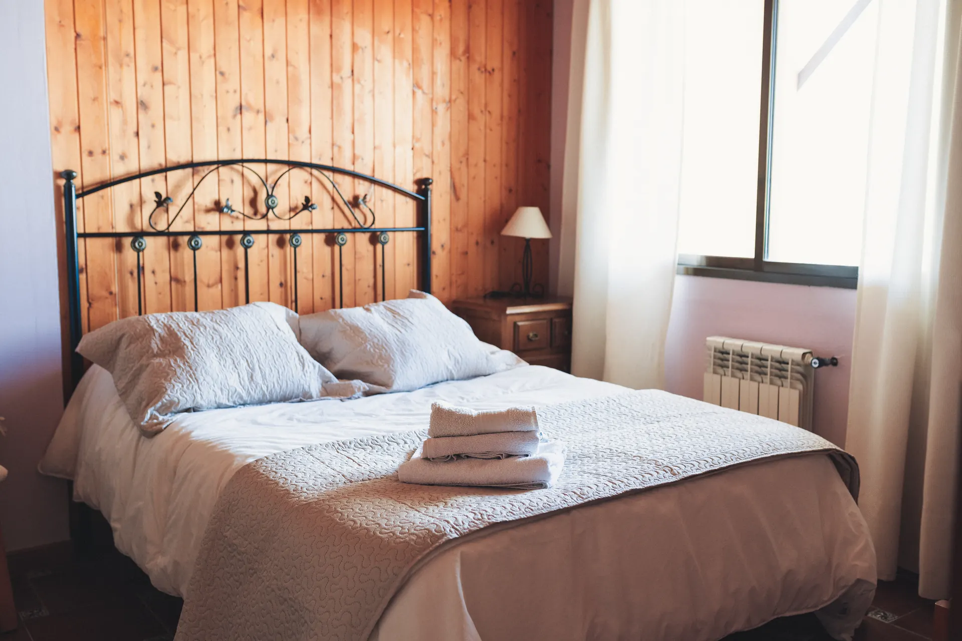 Dormitorio luminoso con cama de matrimonio y cabecero de forja