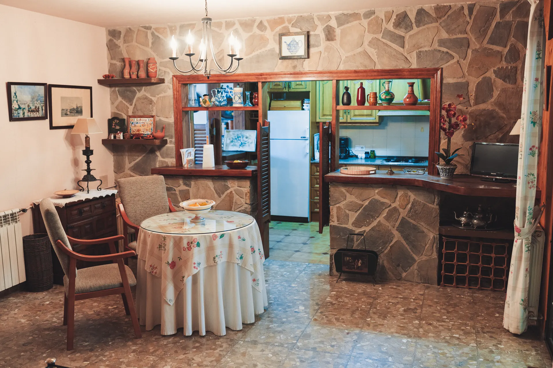 Salón de estilo rústico con pared de piedra y mesa camilla