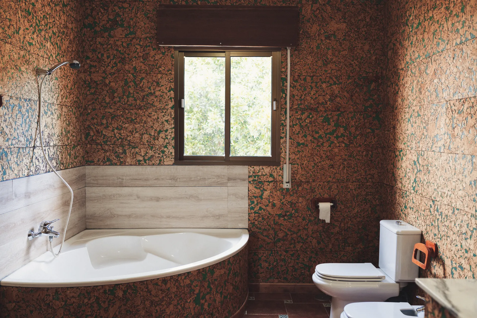 Baño con bañera de esquina y azulejos tipo corcho