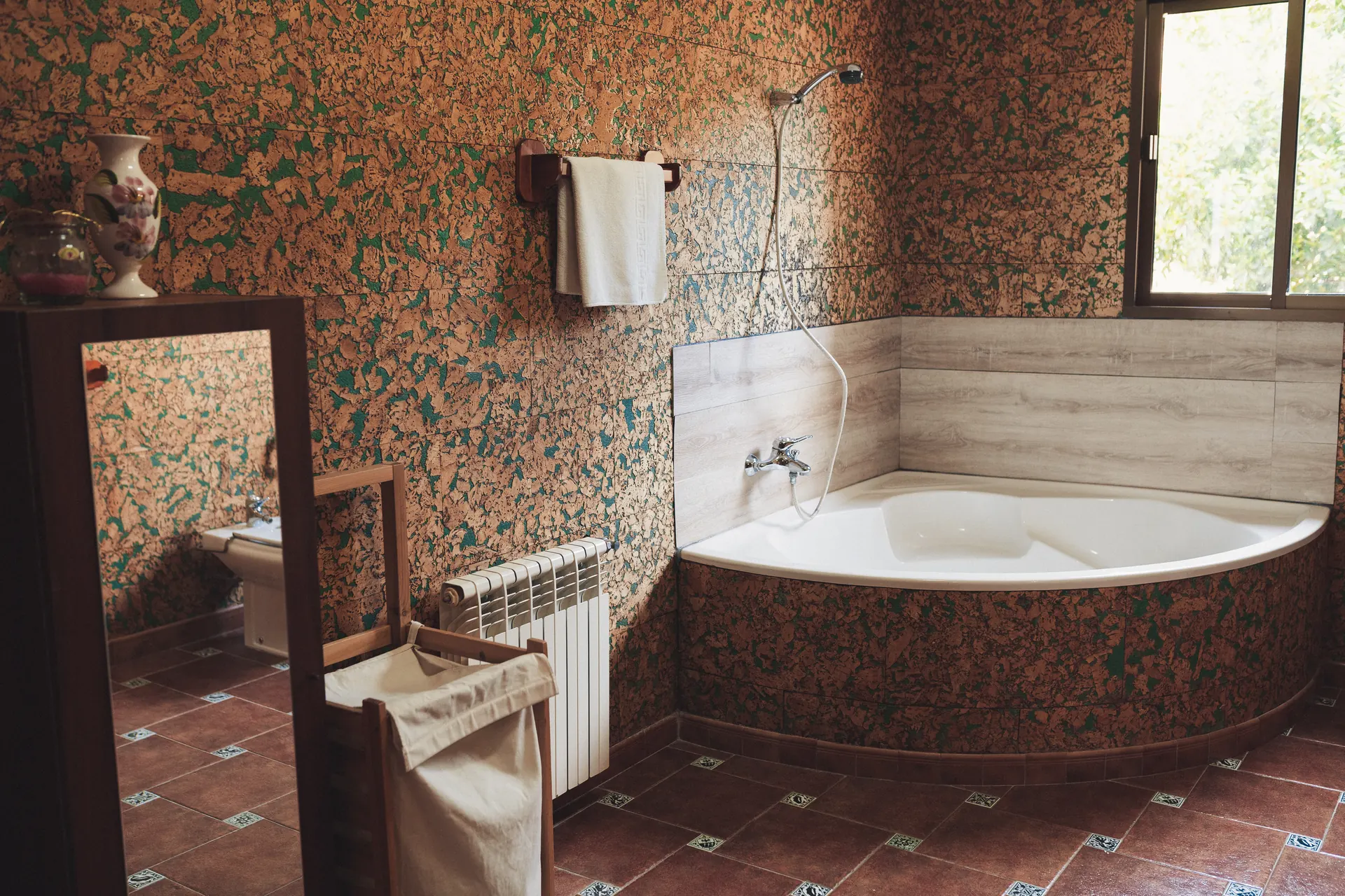 Baño con bañera de esquina y ventana al jardín
