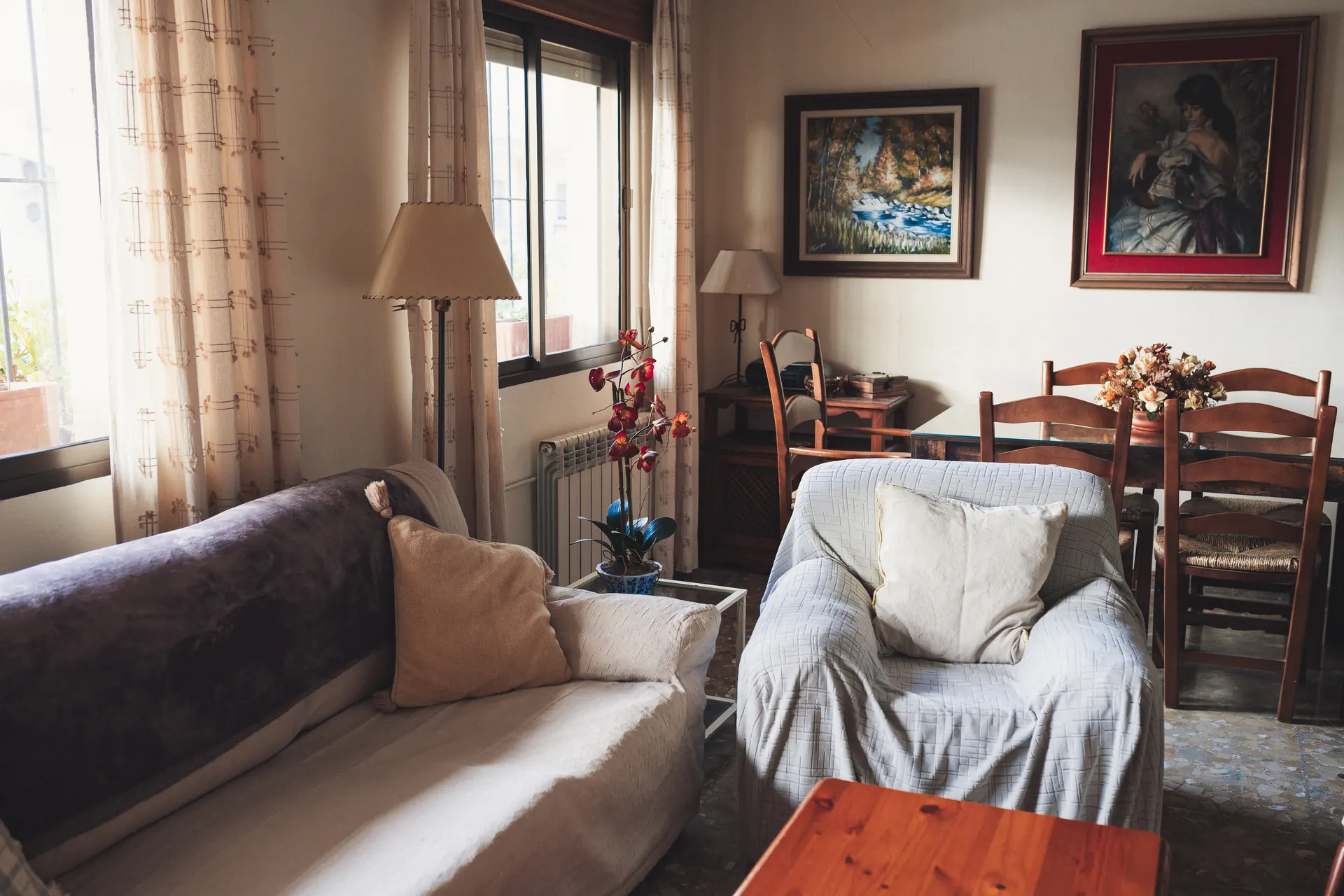 Salón acogedor con sofás claros, lámpara de pie y mesa de comedor al fondo